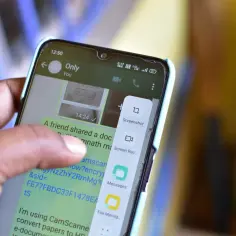 Palec dotyka ekranu telefonu, wybierając opcję "Screenshot", aby zrobić zrzut ekranu.