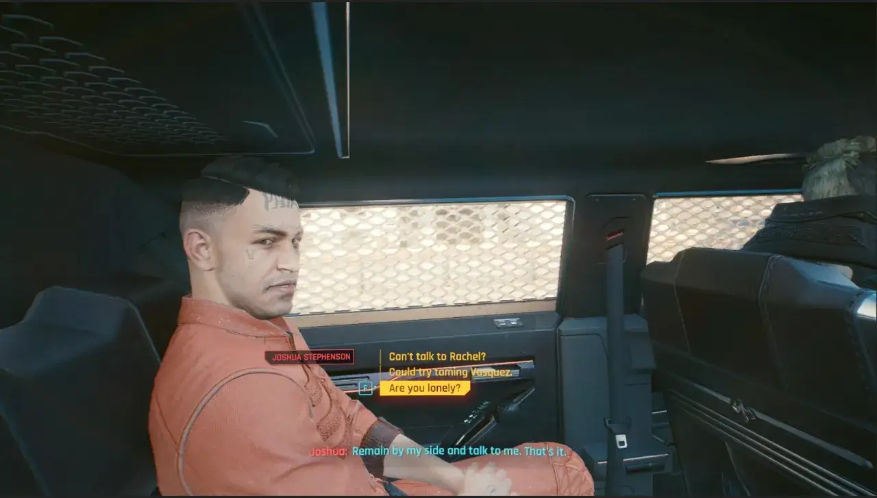 Joshua Stephenson, w pomarańczowym kombinezonie, siedzi w samochodzie. Na jego twarzy widoczny jest znak jonasza cyberpunk.